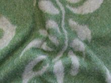 Detailaufnahme eines hochwertigen Jacken-Mantelstoffs in Grün mit weißen, floral inspirierten Mustern. Der weiche, strukturierte Stoff eignet sich ideal für elegante Wintermäntel und stilvolle Übergangsjacken. Perfekt für warme und modische Kleidung.